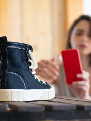 Close-up of sneakers with a woman taking pictures for an online store.