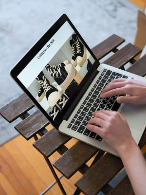 Hands browsing sneakers on laptop, showcasing online store shopping experience.
