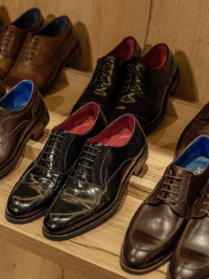 Showcase of elegant leather dress shoes on wooden shelves in-store display.